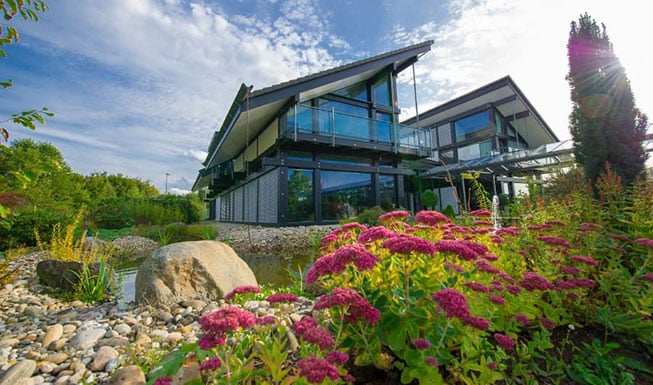 Sonniges Bild des BCT Gebaeudes. Es sind Blume und viel gruenzeug zu sehen