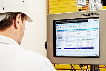 Ein Mann in weißem Hemd und Schutzhelm schaut auf einen Computer.