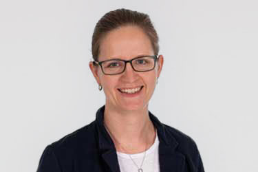 Laechelnde Frau mit Brille im Blazer